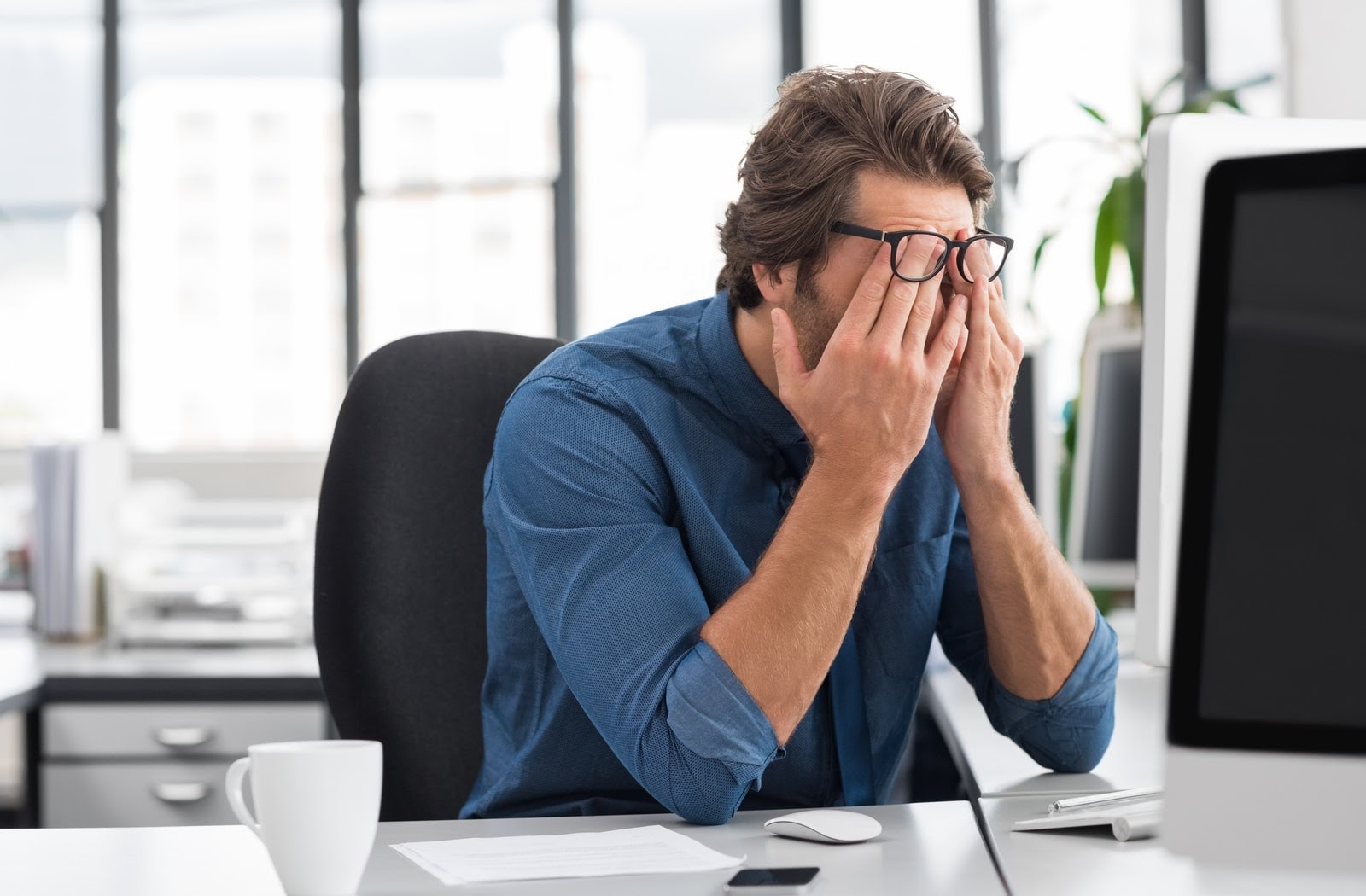 Man sitting at work affected by digital eye strain