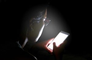 Woman using her bright phone at night affecting her eyes