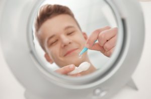 Young boy looking in the mirror taking contact lenses out of the container