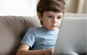 A boy using a laptop that's resting on his lap for an extended period of time making him more likely to develop computer eye syndrome