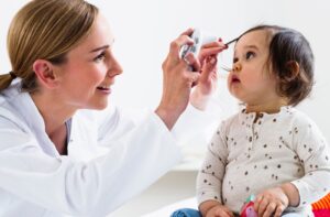 An optometrist checking the eyes of a very young child at their first visit to get their eyes examined