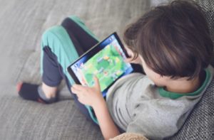 A young boy playing a video game on a tablet