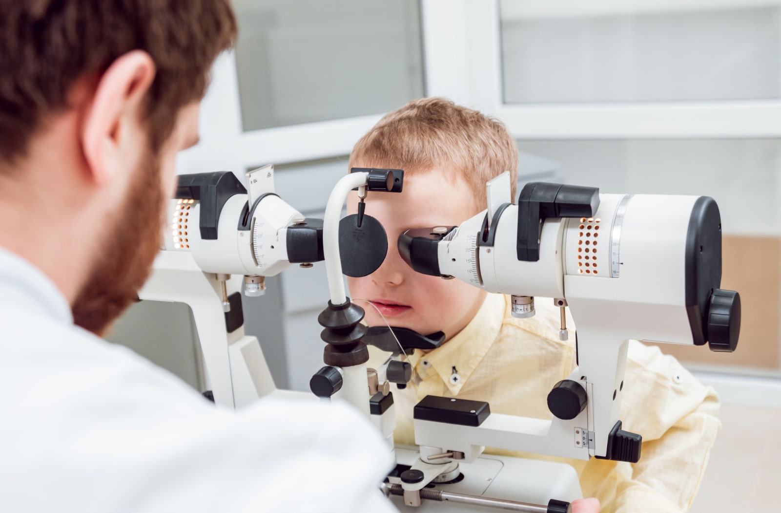 A young boy is having his vision checked by a male optometrist