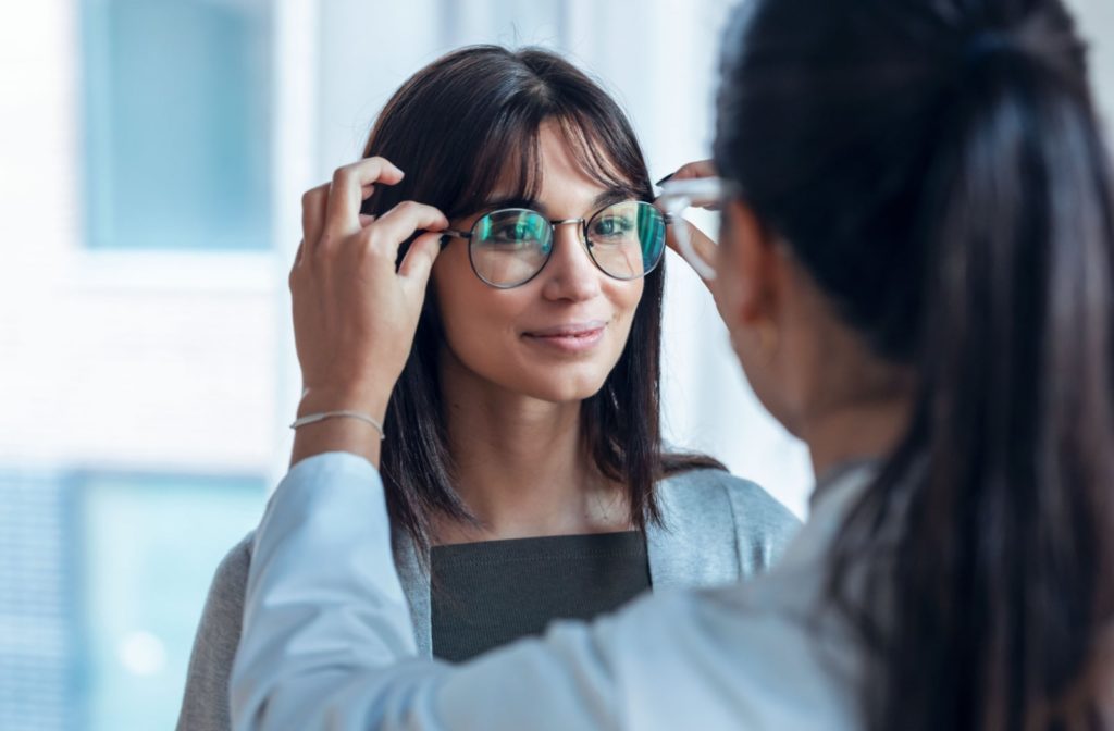 A female optician checking to see if the female patient's glasses are sitting on her face correctly