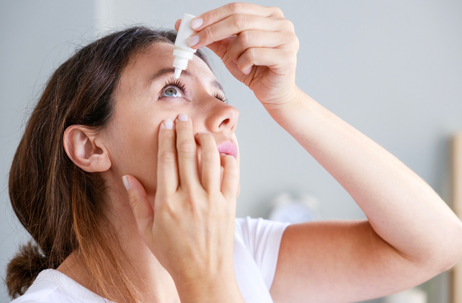 Woman putting non-expired eye drops in her right eye