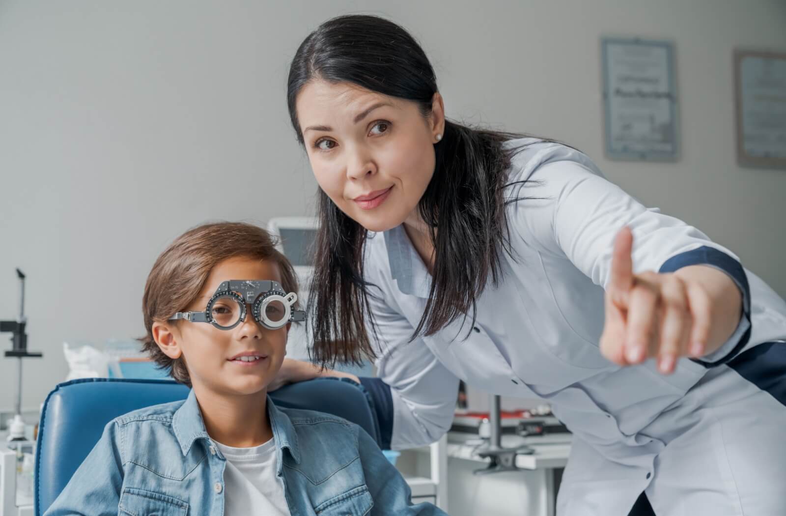 A female optometrist gesturing while testing a child's vision for astigmatism.