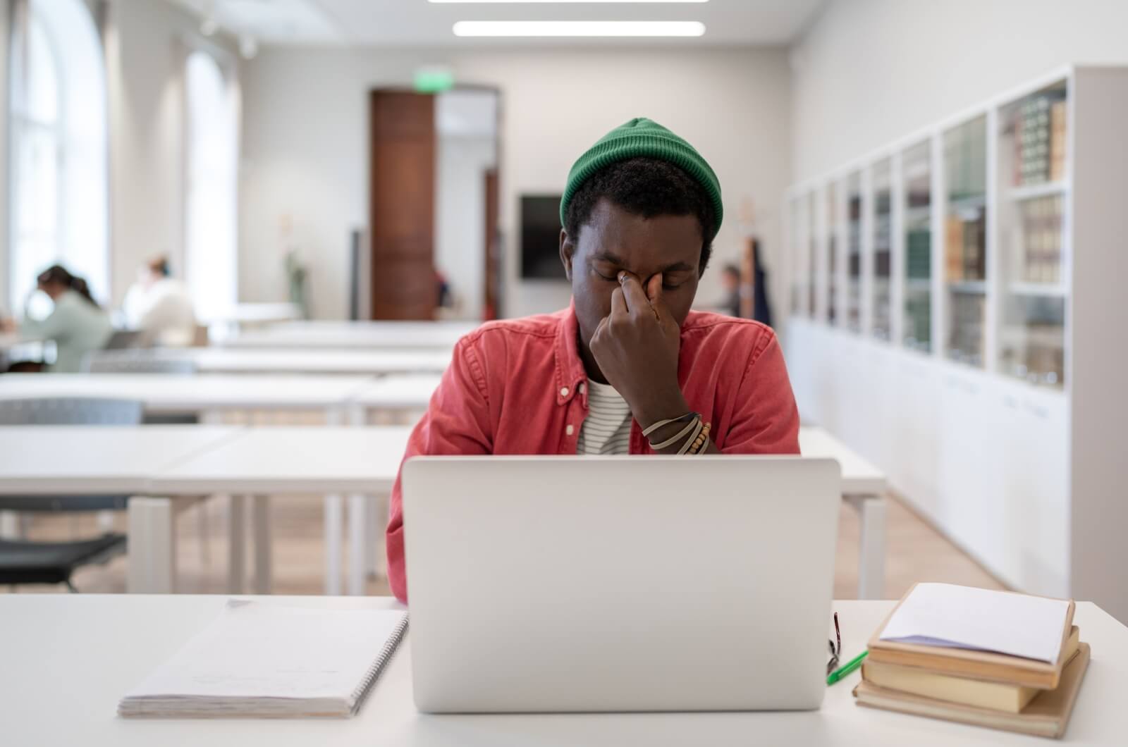 Adult man working on laptop, rubbing his eyes from eye strain.