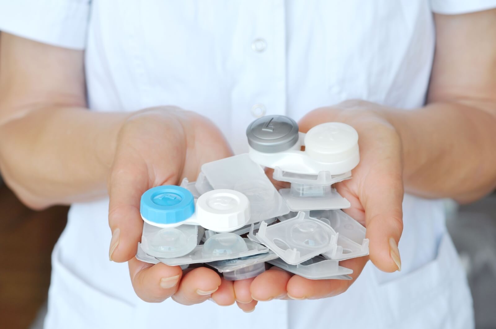 A close-up of an optometrist holding a variety of contact lenses in the palm of their hand.