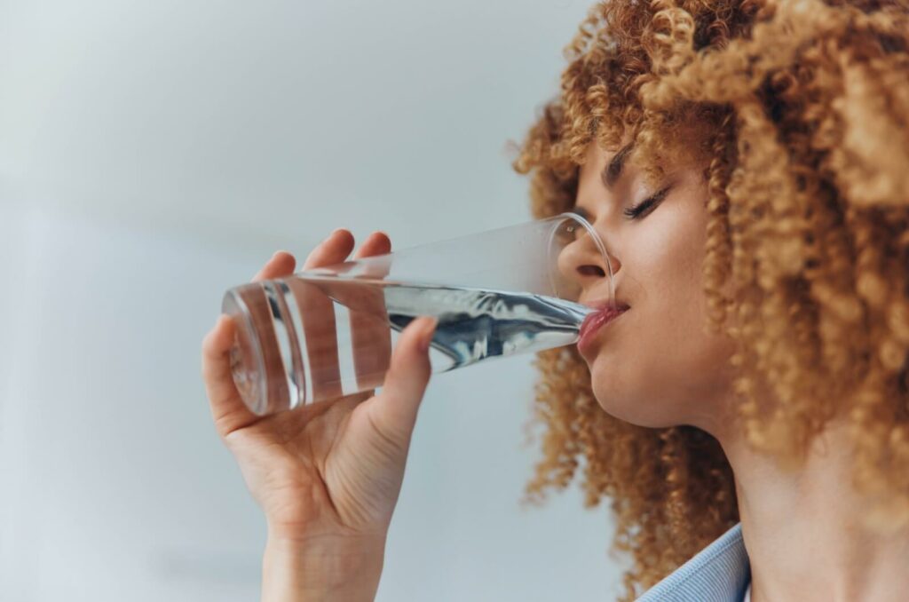 A person staying hydrated by drinking a glass of water to maintain their eye health.