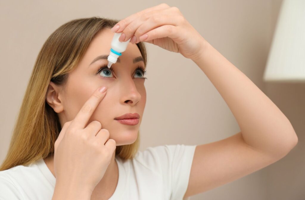 A women looking up while putting eye drops in their right eye.