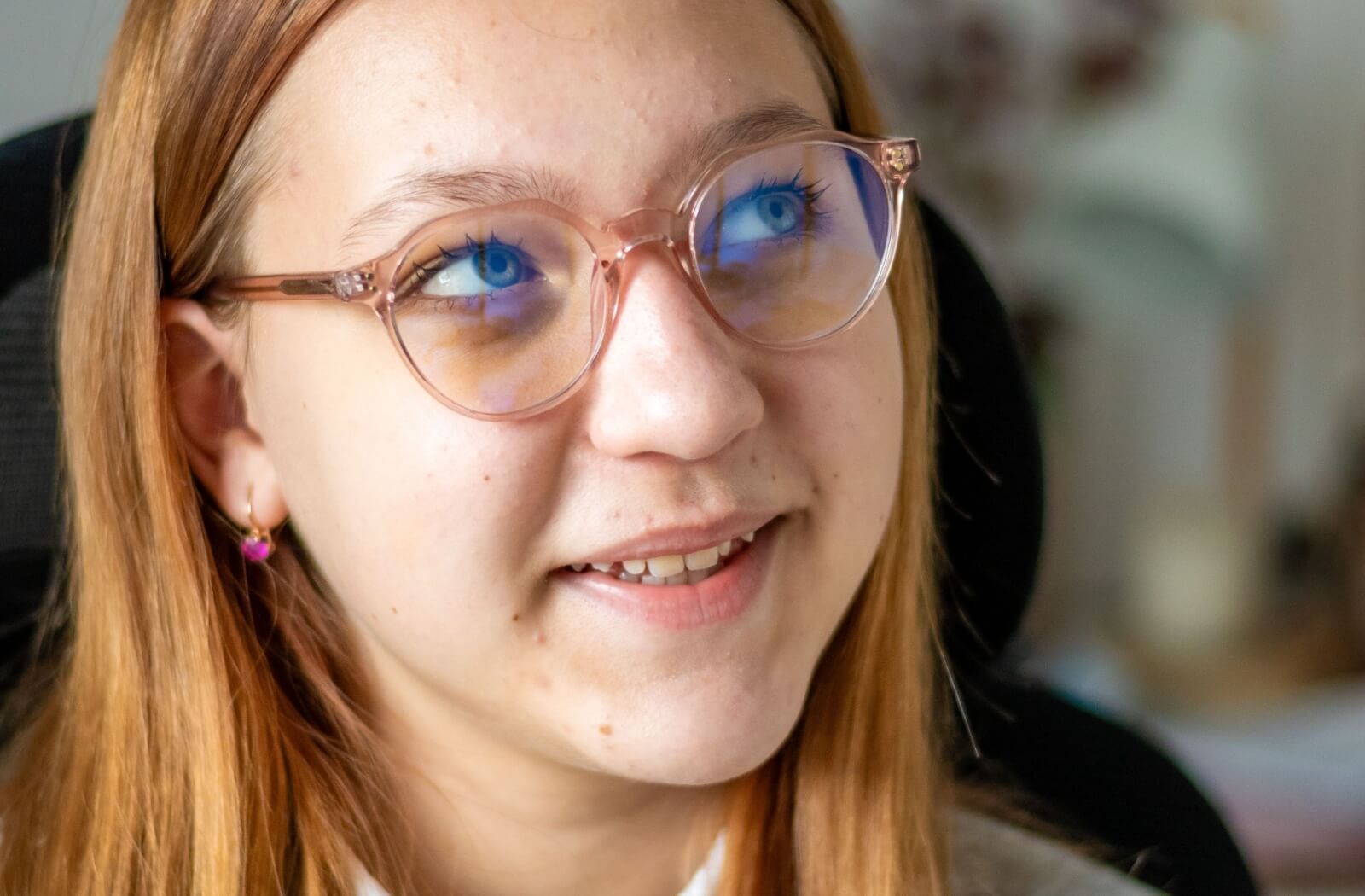 Close-up of young person wearing rose-tinted screen glasses with a faint blue reflection.
