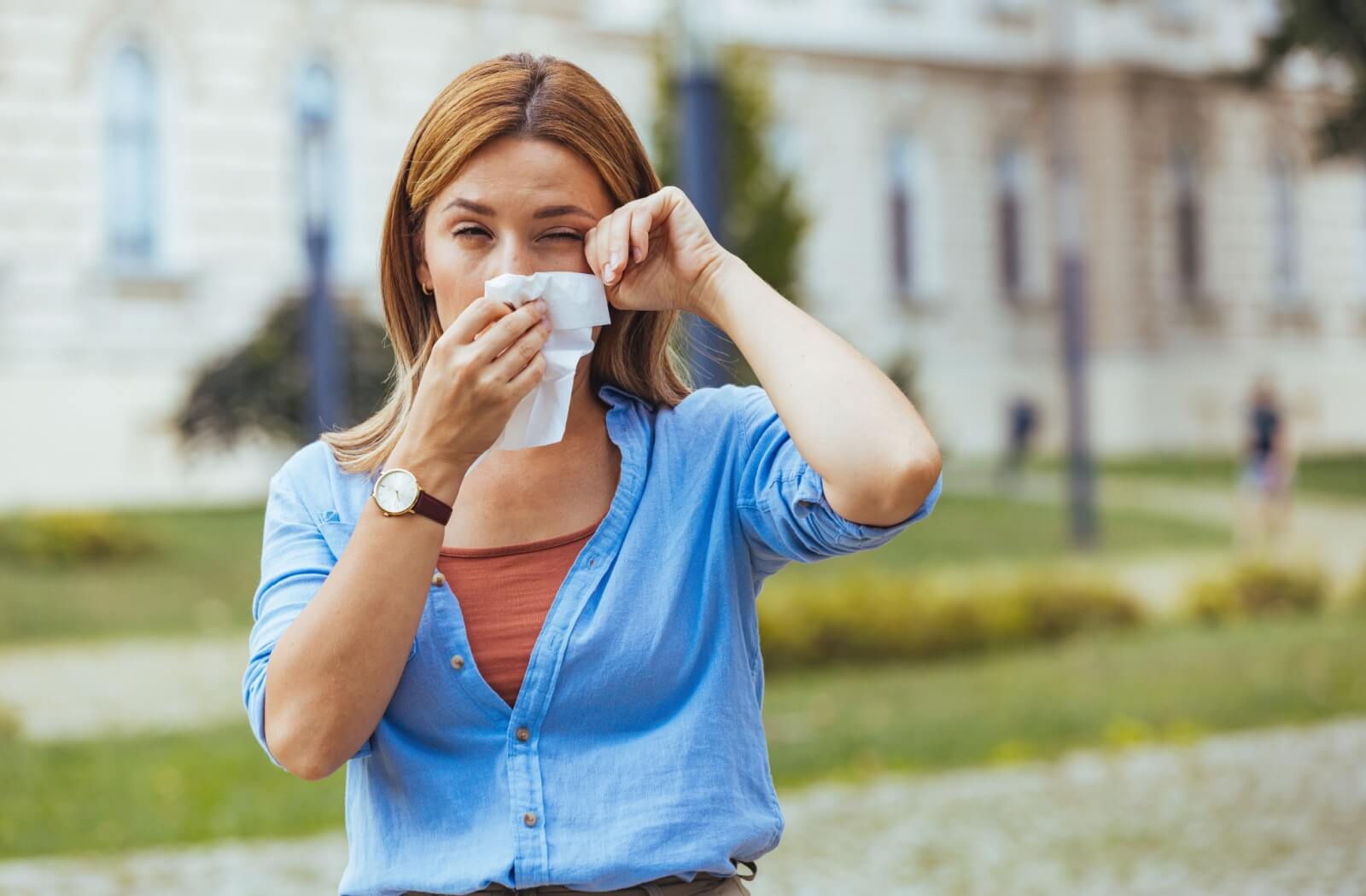 Woman wiping her eyes with a tissue experiencing stinging or eye irritation.