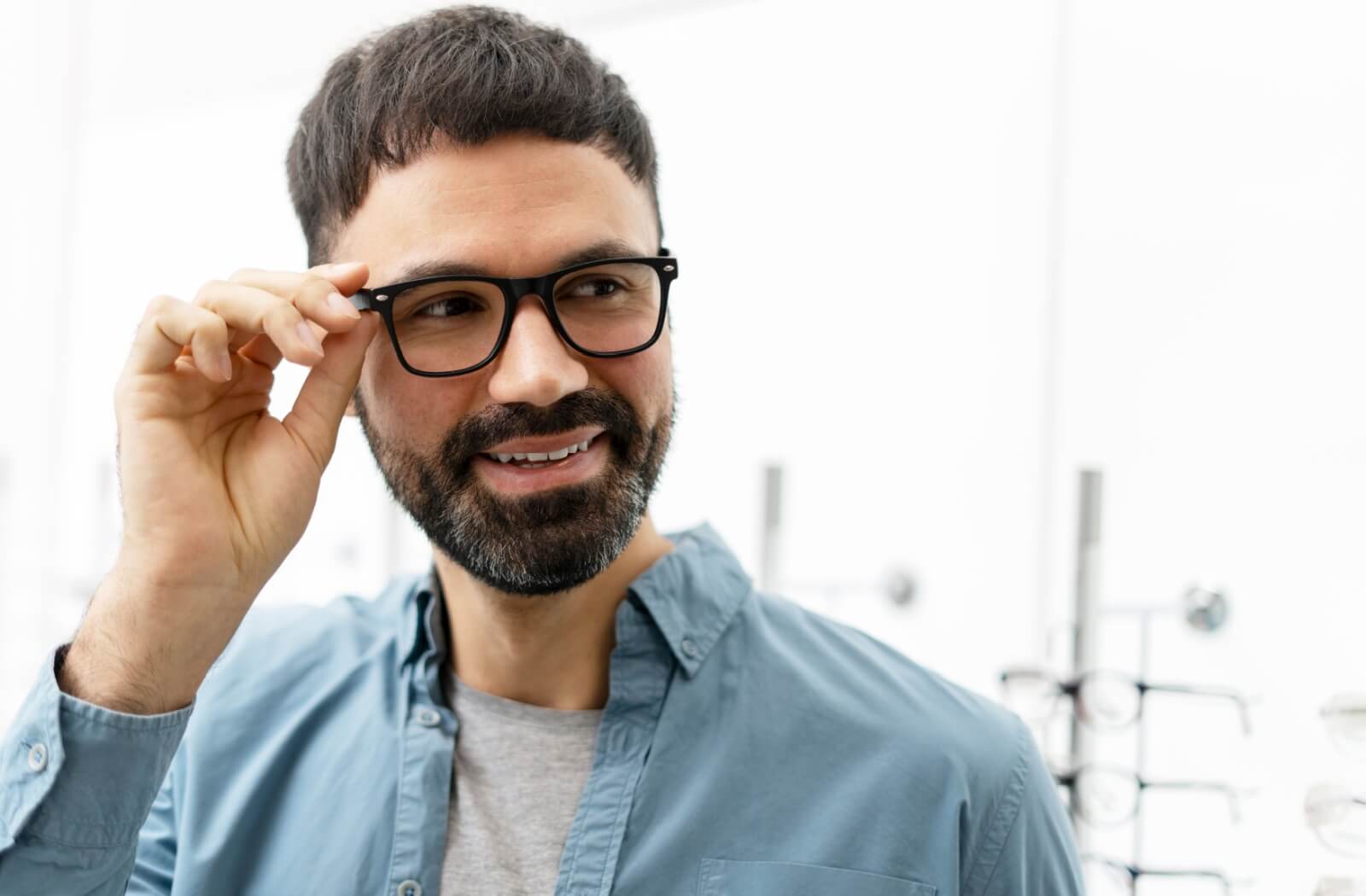Someone adjusts their glasses while trying on new frames at their optometrist.