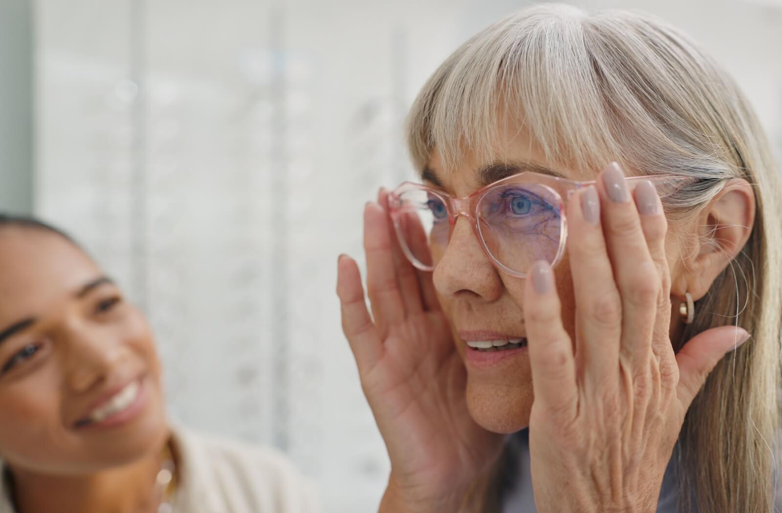 An optician helps someone try on their new prescription lenses in-store.