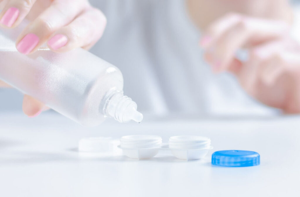 A person squeezes contact lens solution into a contact lens case as a part of their contact lens care routine.