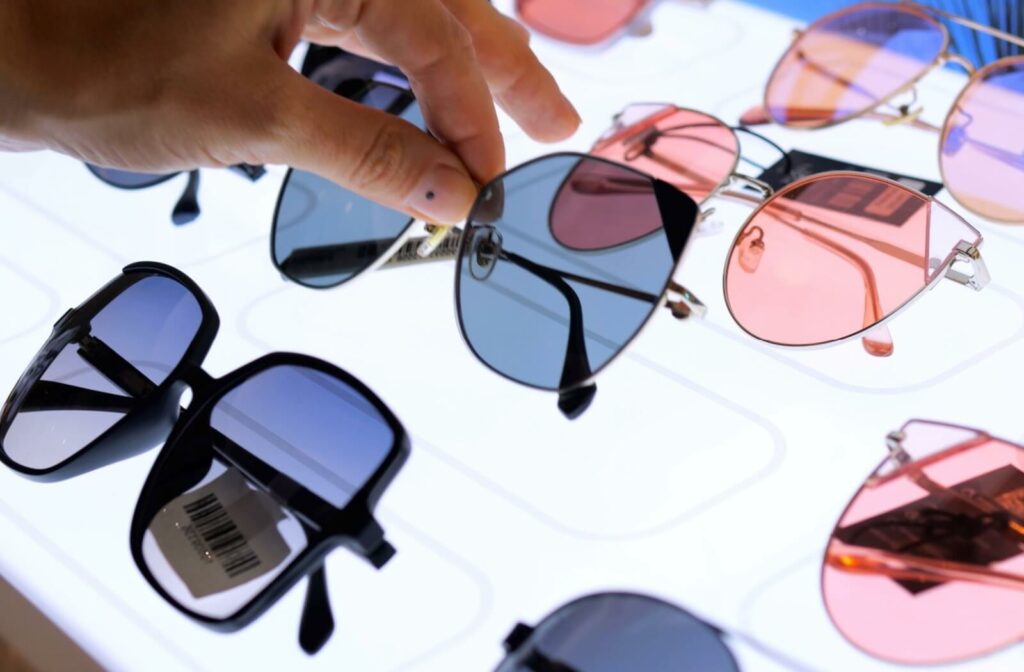 A person reaches out and picks up a pair of trendy, polarized sunglasses in a sunglasses display.