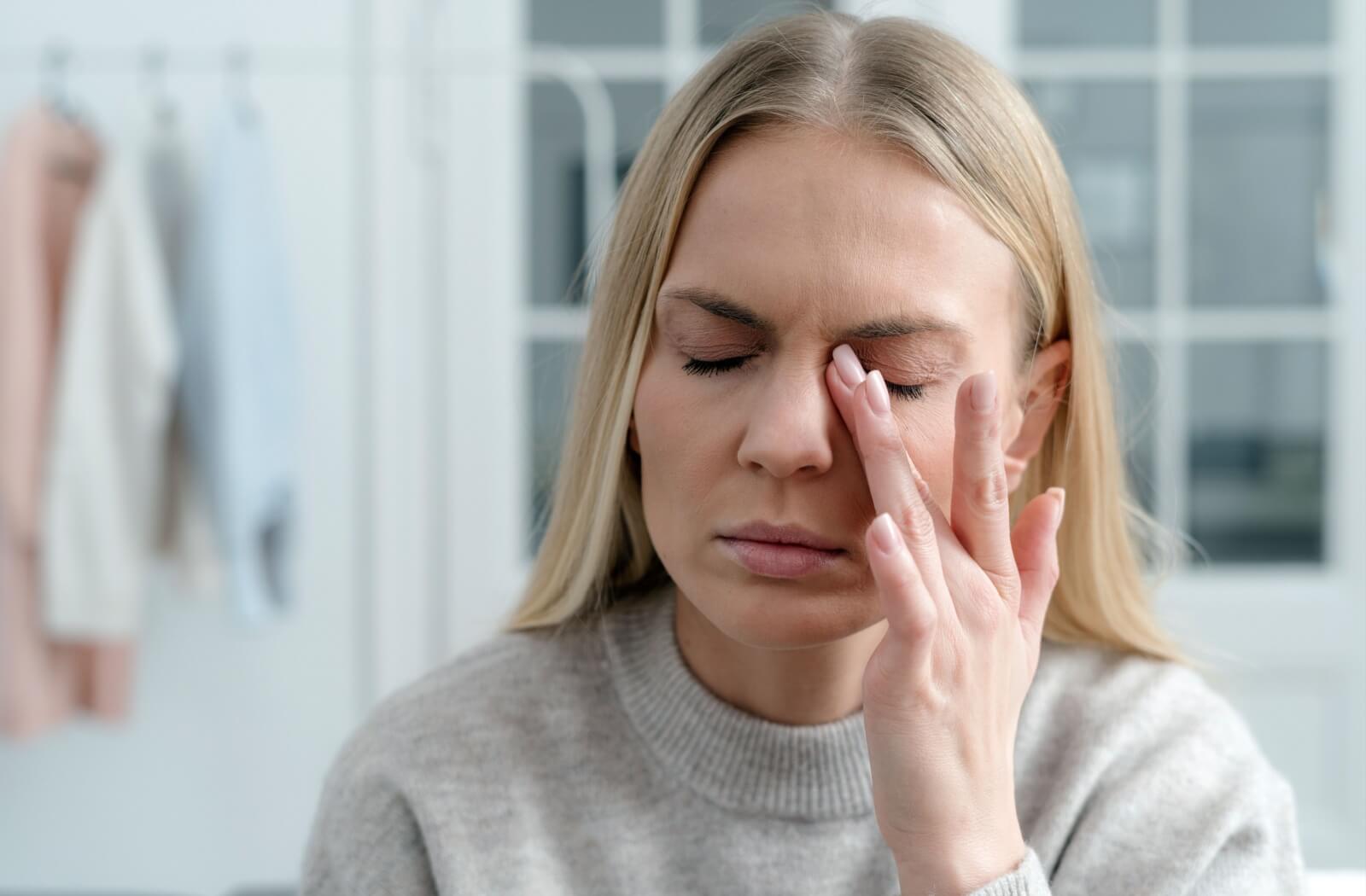 A person rubbing her eye in discomfort, showing signs of eye irritation or dryness.