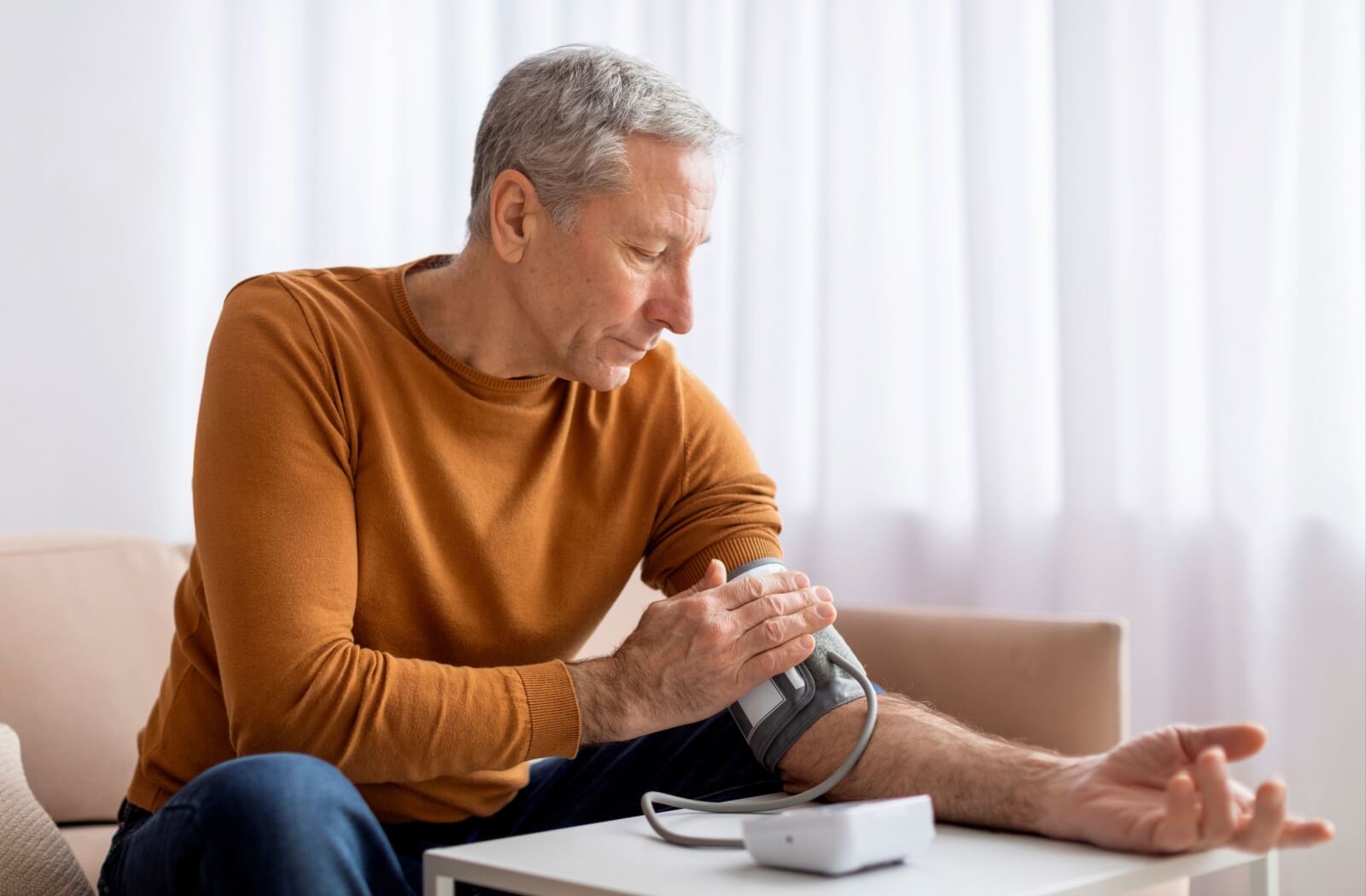 Person checking blood pressure at home using an upper arm monitor, illustrating high blood pressure as a potential cause of flashing lights or visual disturbances in the eyes.
