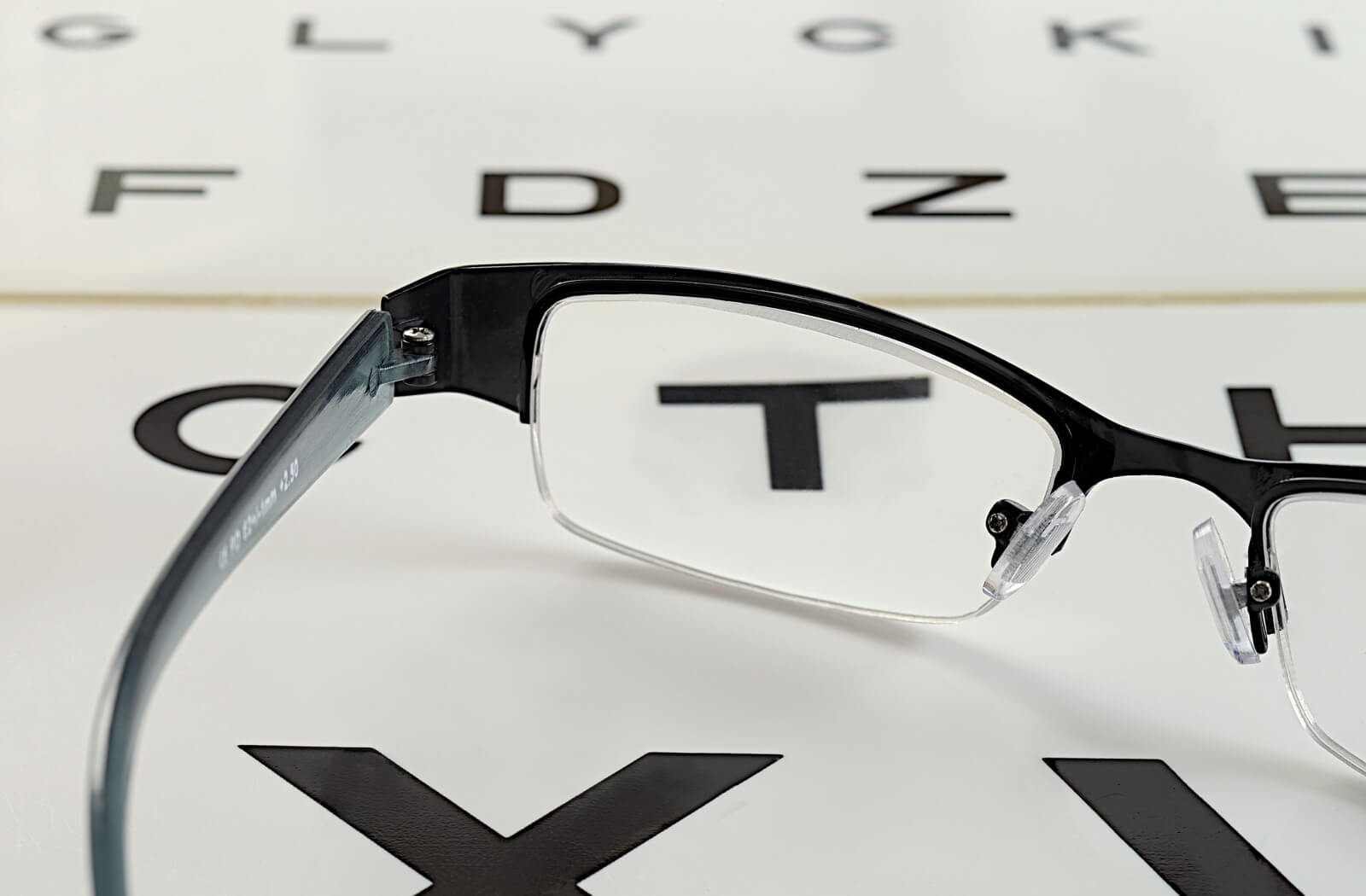 Close-up of eyeglasses positioned over an eye chart, illustrating vision correction and prescription testing.