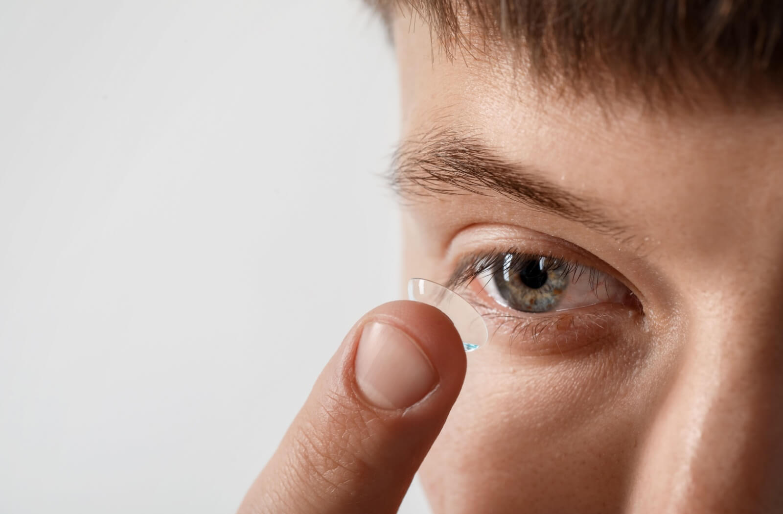 A close-up view of an individual preparing to insert a soft contact lens into their eye.